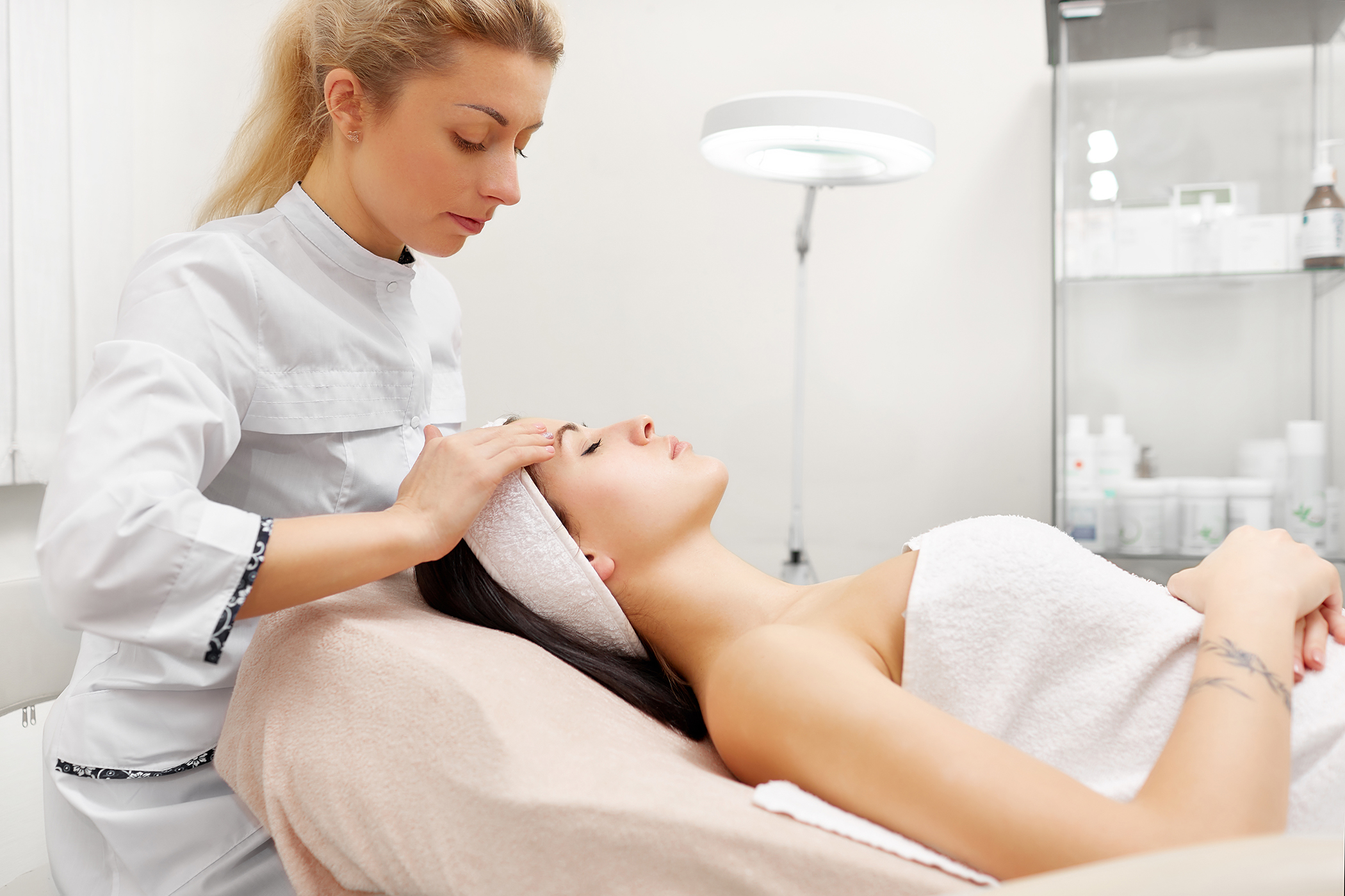 beauty therapist assessing a clients skin in beauty salon