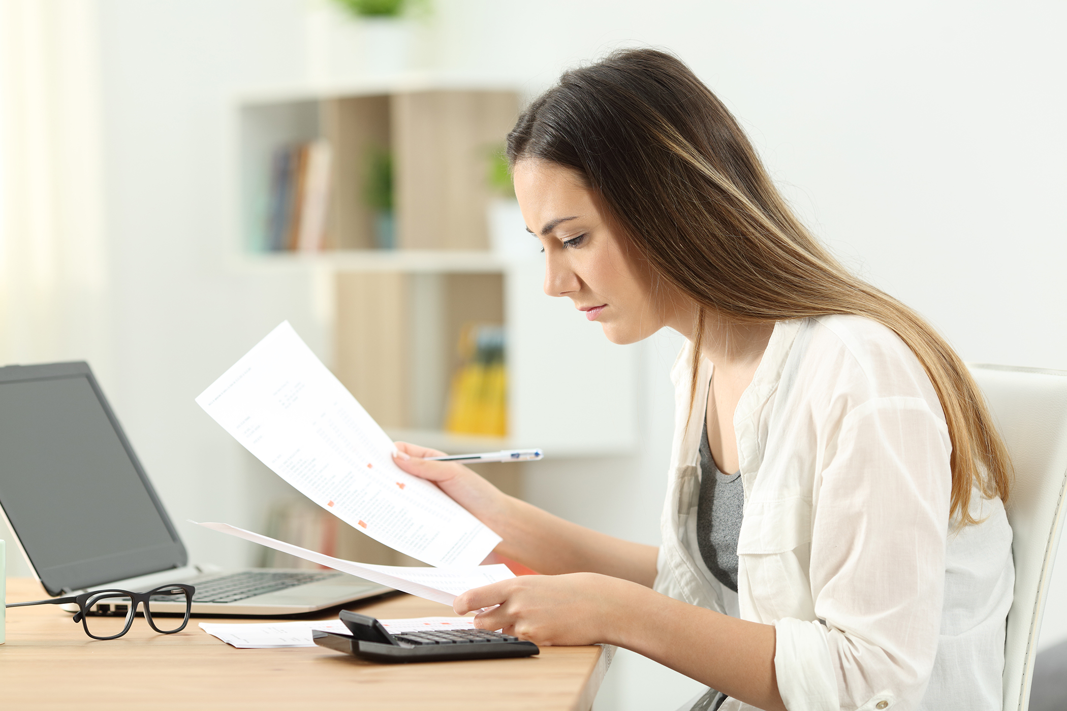 woman checking financial paperwork with laptop