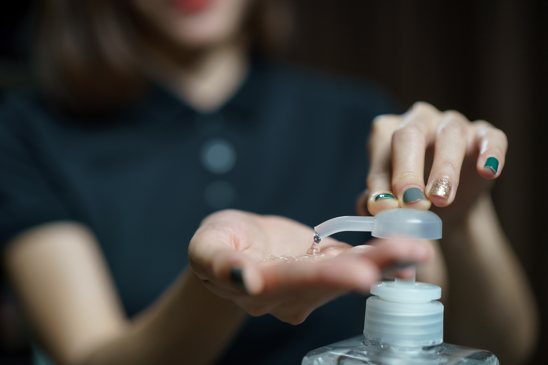 Beauty therapist using hand sanitizer in salon